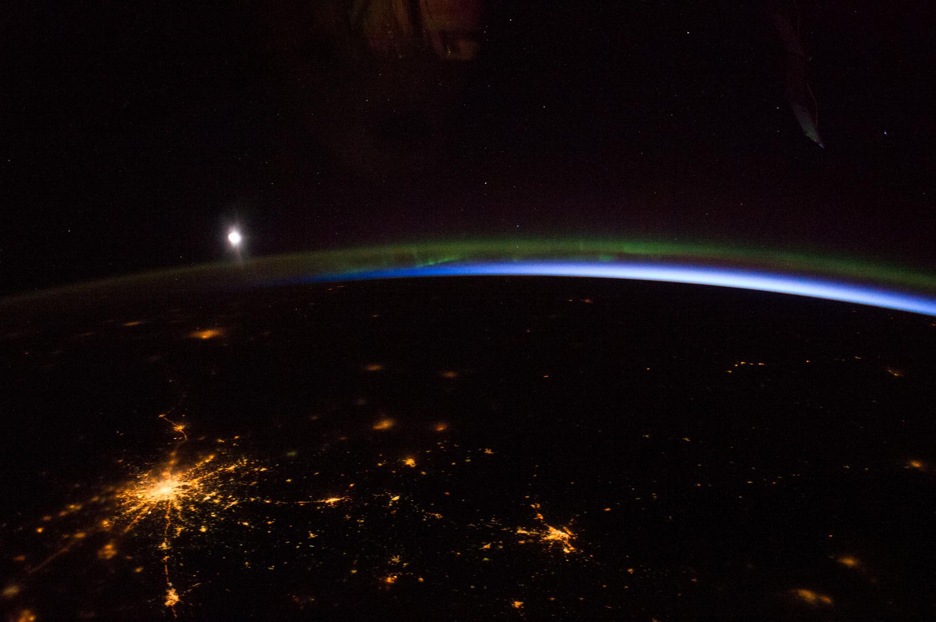 Aurora borealis from the ISS with city lights and the moon below