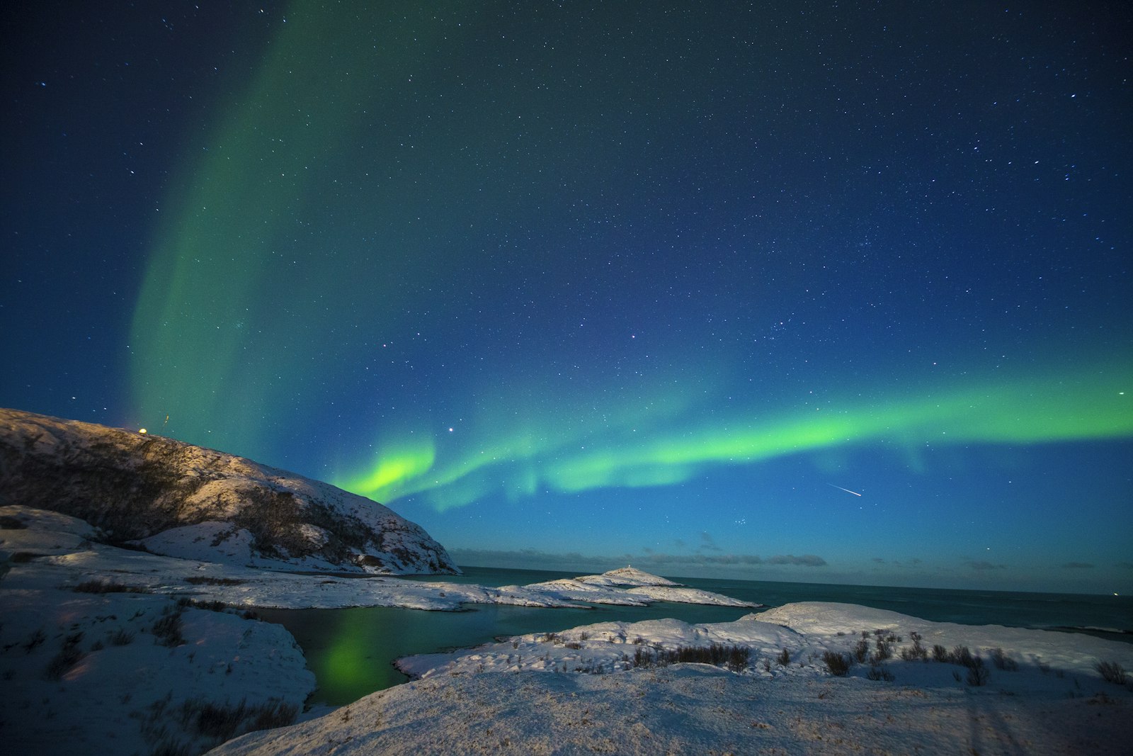 Aurora borealis above a snowy coast in Tromsø, Norway